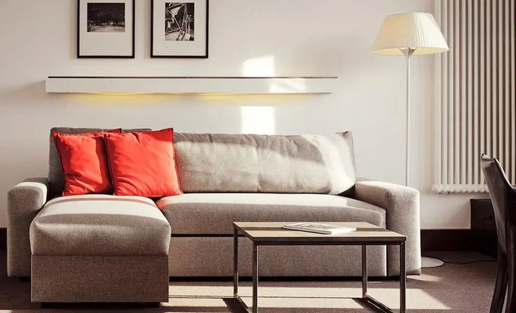 Moderne Sitzecke im XXL Doppel Loft mit eleganter grauer Couch und roten Kissen