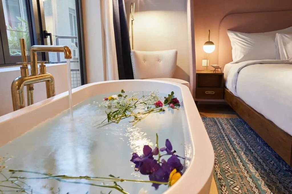 Entspannendes Badezimmer mit Blumen in der Badewanne und Leselampe