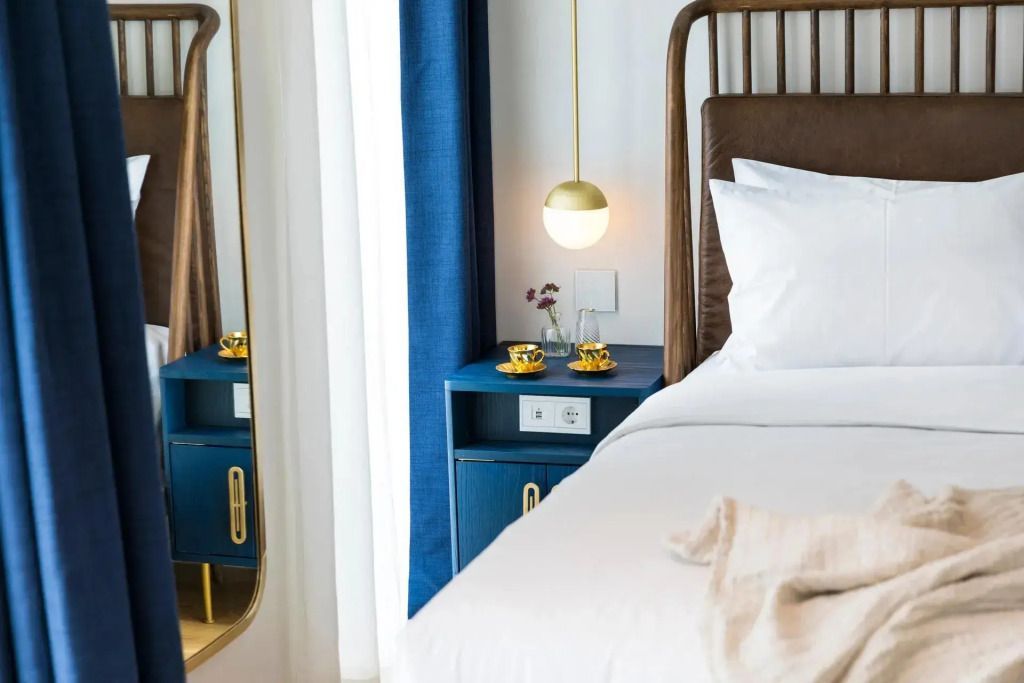 Detailansicht eines Bettes mit Nachttisch und edler Lampe.