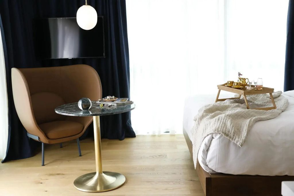 Moderner Tisch mit Sessel und Bett in Suite mit hellem Holzfußboden