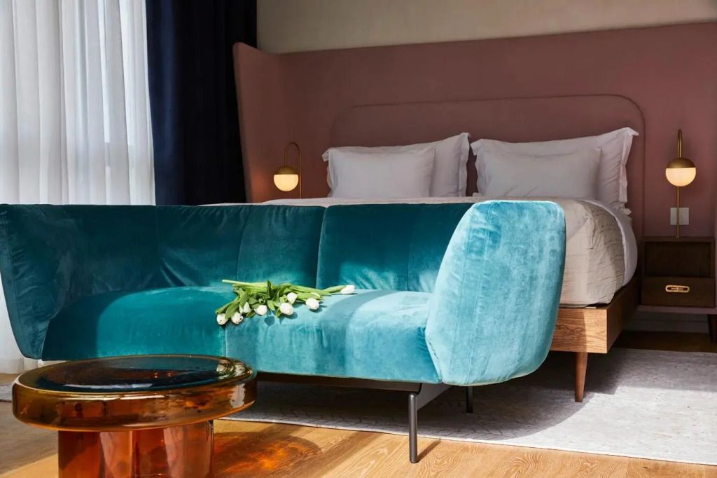 Türkises Sofa und Doppelbett mit pastellfarbenem Kopfteil in Suite