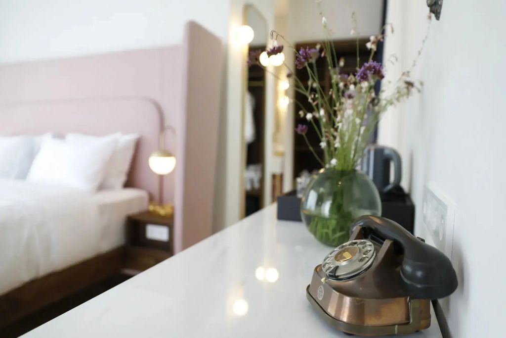Retro-Telefon und Blumen auf Tisch vor Bett in moderner Suite