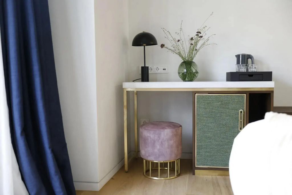 Schreibtisch im Hotelzimmer mit moderner Beleuchtung und Blumenarrangement