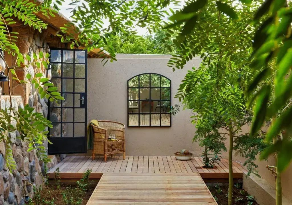 Privater Gartenbereich mit Holzsteg und Sitzgelegenheit umgeben von üppigem Grün.