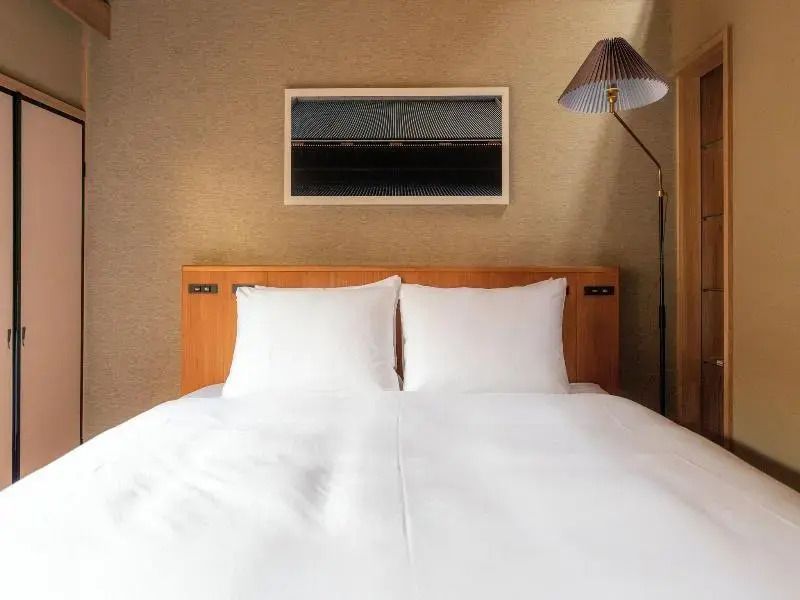 Modernes Doppelbett im Standard Zimmer mit stilvoller Wandlampe
