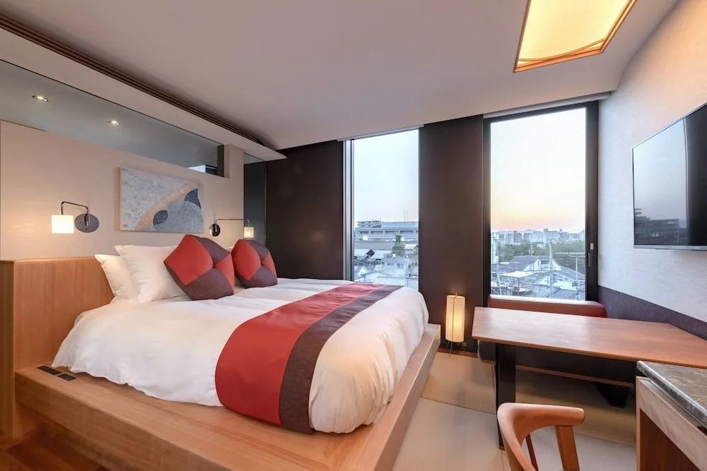 Modernes Hotelzimmer mit großem Bett und zwei Panoramafenstern mit Stadtblick
