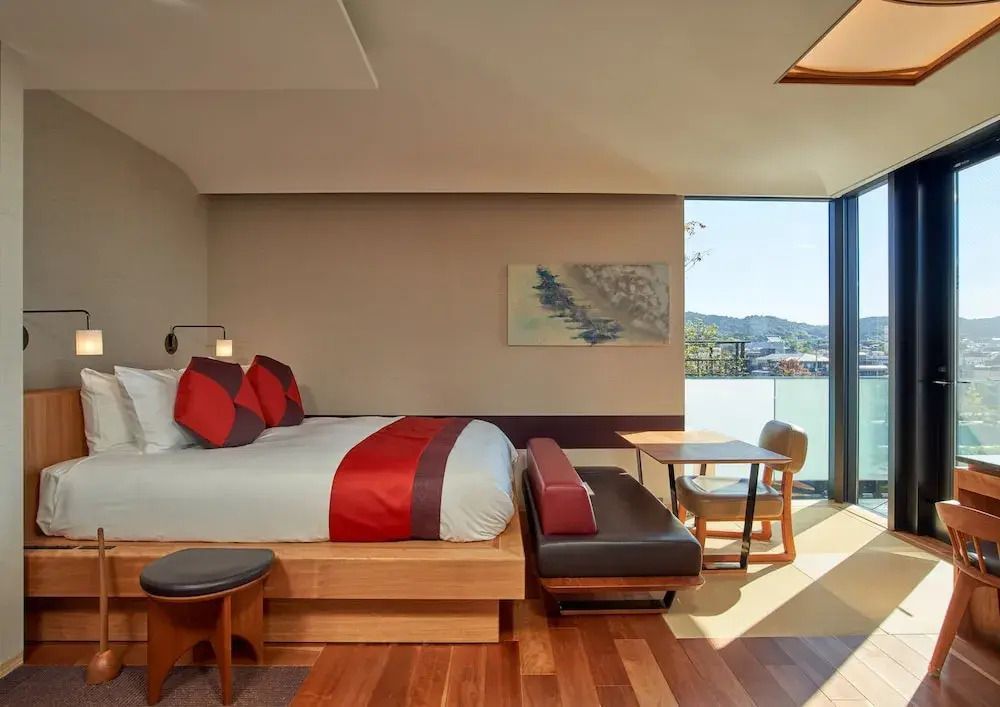 Modernes Hotelzimmer mit Kingsize-Bett, roten Akzenten und Balkonblick.