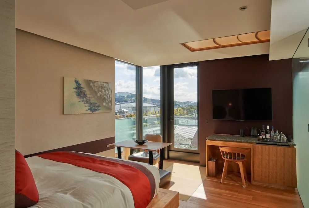 Hotelzimmer mit großem Fenster, Blick auf die Stadt und gemütlichem Arbeitsbereich.