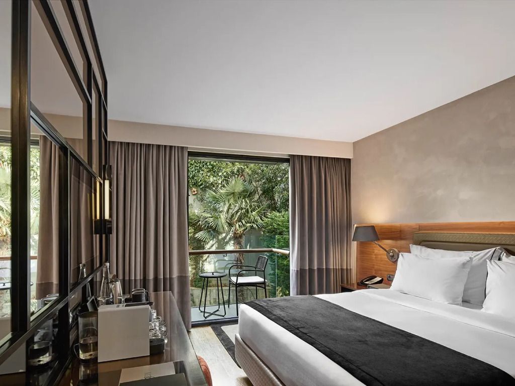 Deluxe Doppelzimmer mit Blick auf einen grünen Garten und einem gemütlichen Bett.