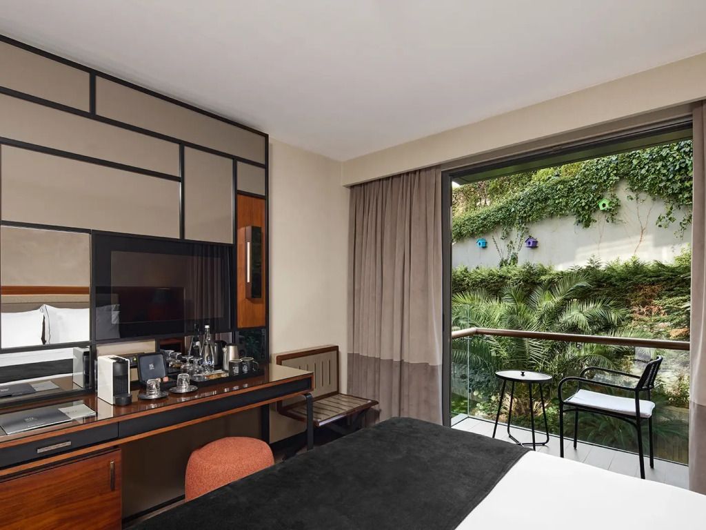 Modernes Zimmer mit Schreibtisch und Aussicht auf bewachsenen Gartenbalkon.