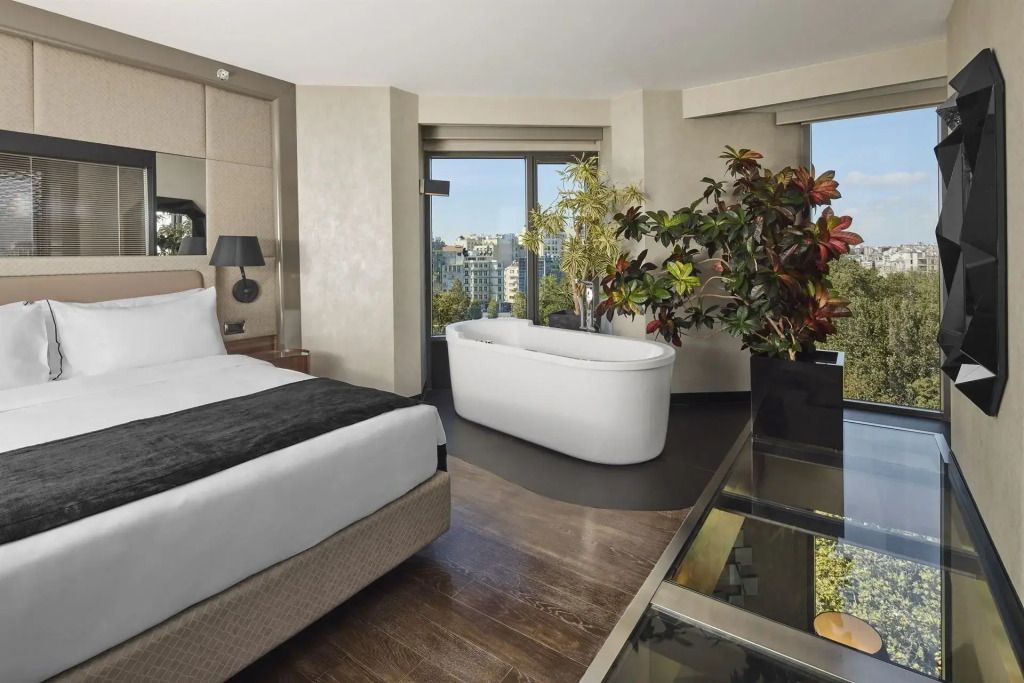 Schlafbereich der Suite mit freistehender Badewanne und Panoramafenster