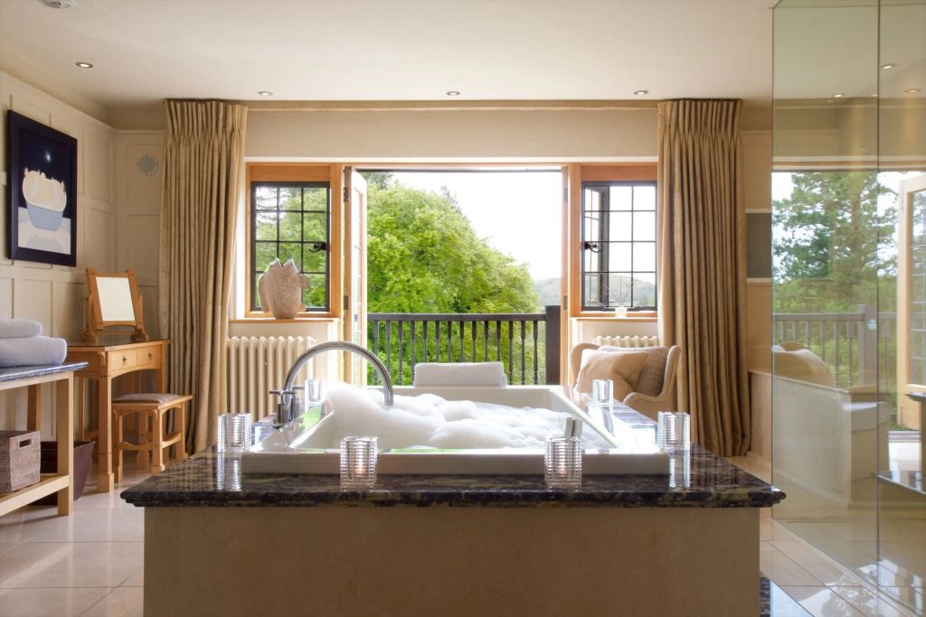 Jacuzzi im Raum der Spa Suite mit Blick auf den Balkon und Natur
