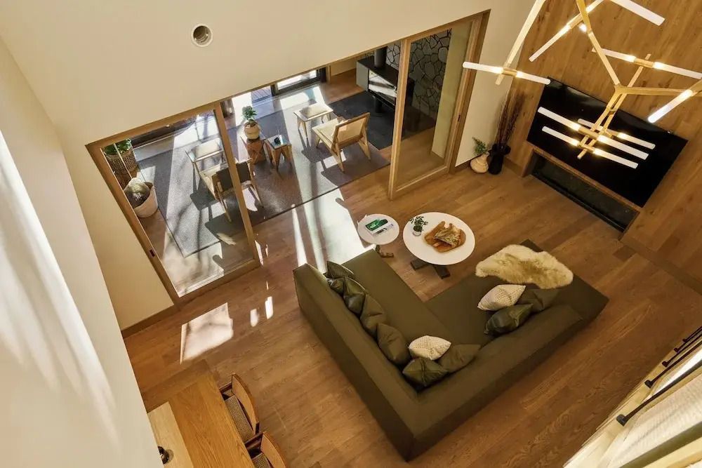 Blick von oben auf ein gemütliches Wohnzimmer mit großem Sofa und Zugang zum Balkon