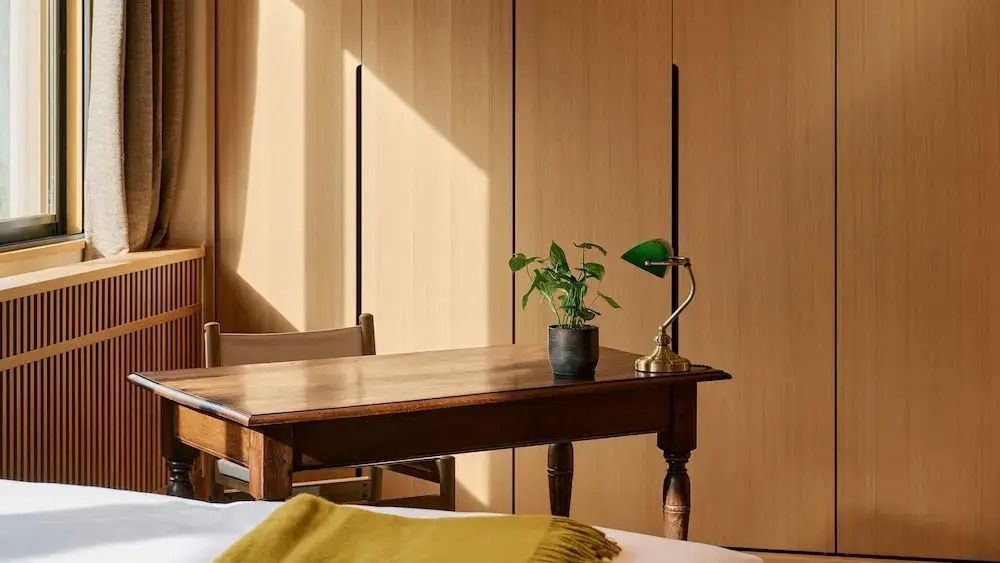 Sonnendurchfluteter Tisch mit Pflanze und klassischer Lampe in einem Luxuszimmmer.