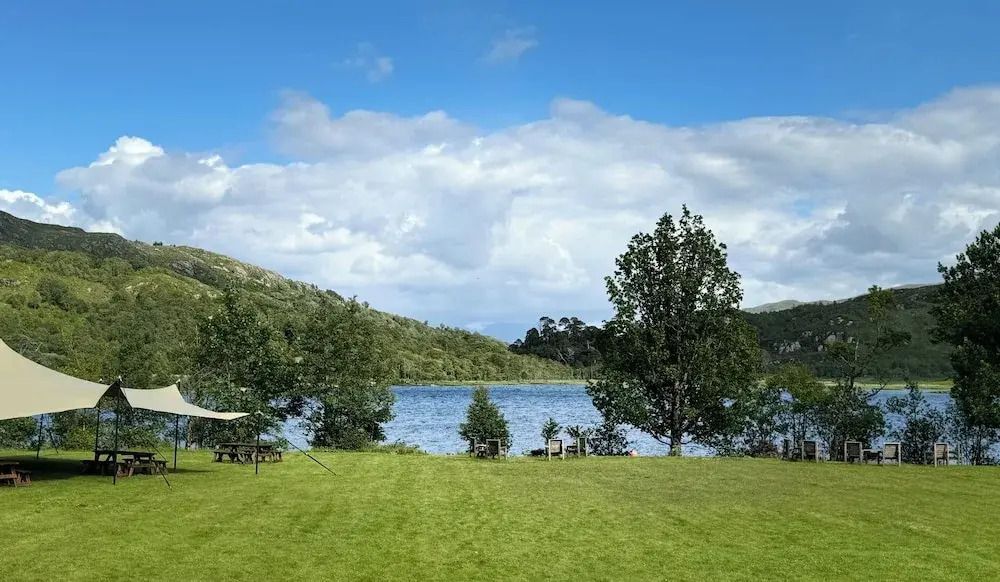 Grüner Garten mit Blick auf einen See und bewaldete Hügel