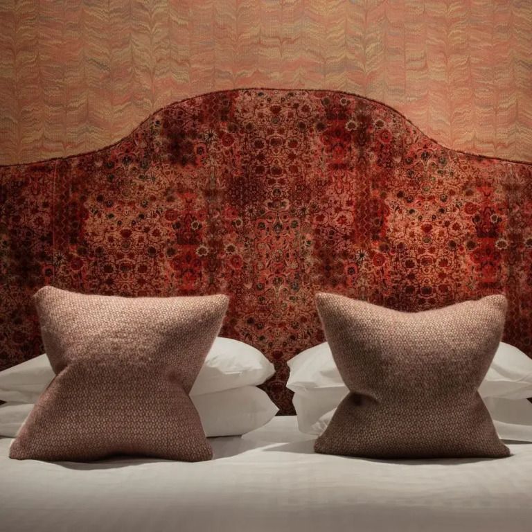 Doppelbett mit kunstvollem Kopfteil in warmen Rottönen im Superior Zimmer