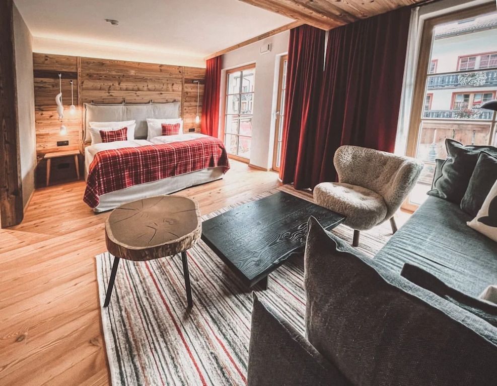 Gemütliche Junior-Suite mit Holzakzenten, Doppelbett und gemütlicher Sitzecke.