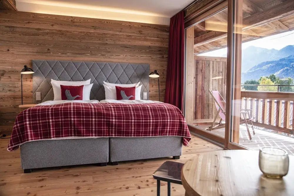 Junior-Suite mit Doppelbett, roten Akzenten und Zugang zum Balkon.