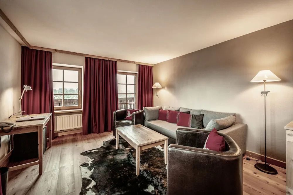 Wohnbereich der Suite mit großen Fenstern, gemütlicher Sitzecke und stilvoller Einrichtung.