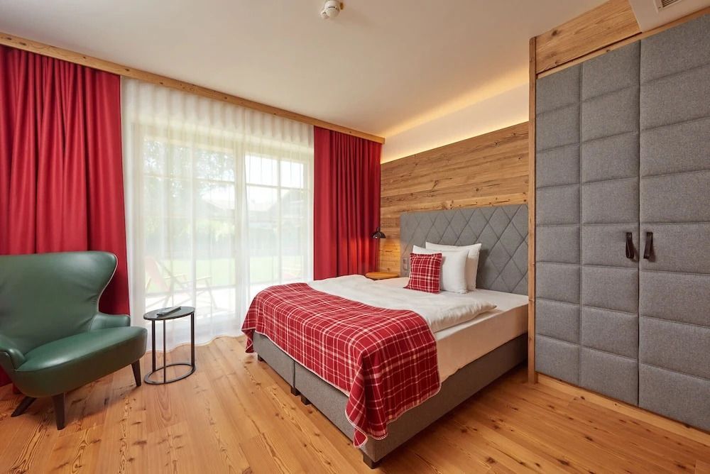 Helles Zimmer mit großem Fenster und rotem Dekor im Hotel Das Achental