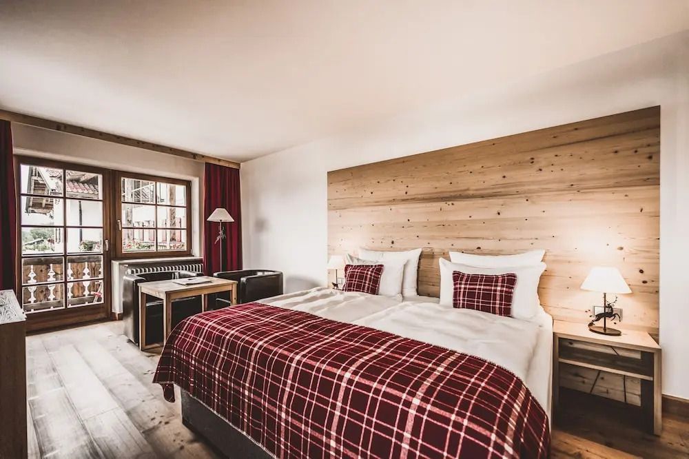 Hotelzimmer mit Doppelbett in Rot- und Holztönen und Sitzbereich