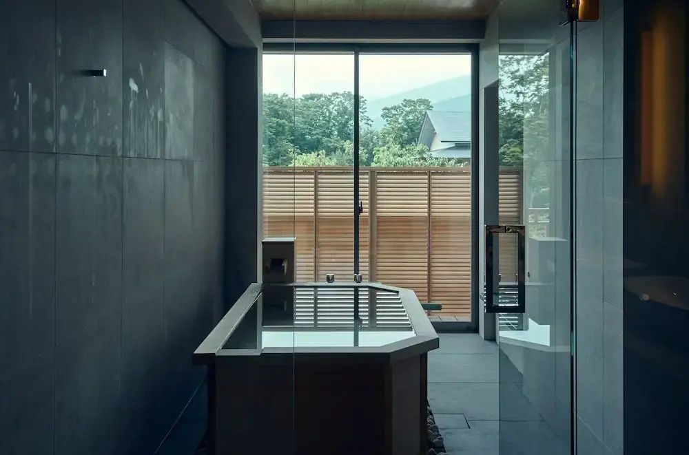 Modernes Badezimmer mit großer Wanne vor Fenster und Blick auf grüne Landschaft