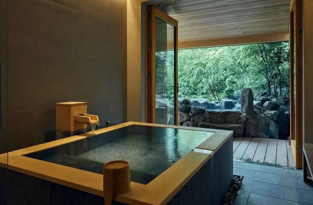 Warmes Onsen mit Blick auf natürliche Felsen und Bambusgarten