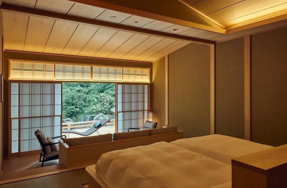 Geräumiges Zimmer mit großen Fenstern und Blick auf die Natur im Hintergrund