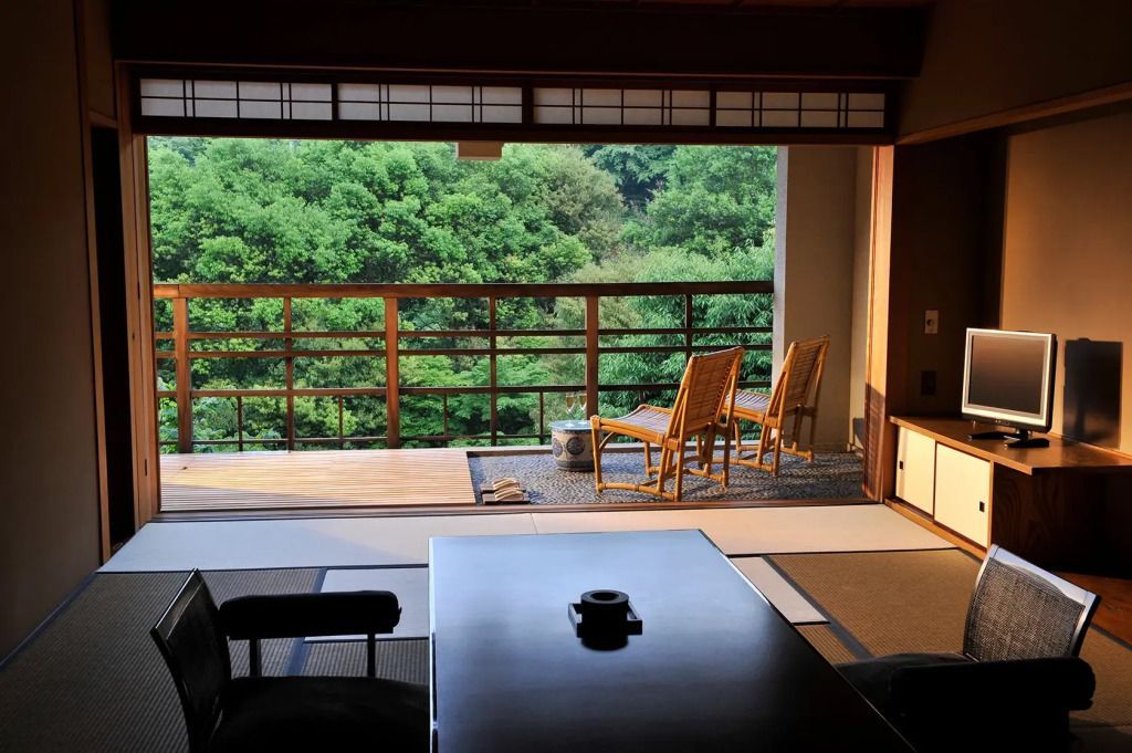 Traditionelle japanische Suite mit Blick auf einen grünen Wald von einem privaten Balkon aus.