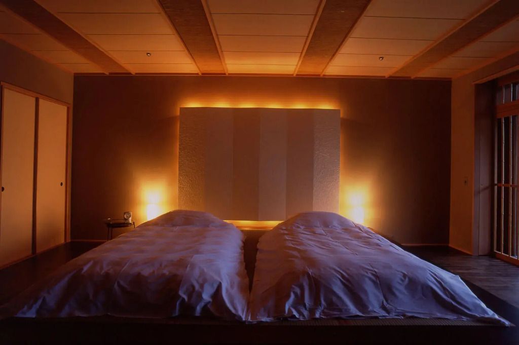 Stimmungsvolle Beleuchtung im Schlafzimmer mit zwei bequemen Einzelbetten und minimalistischem Design.