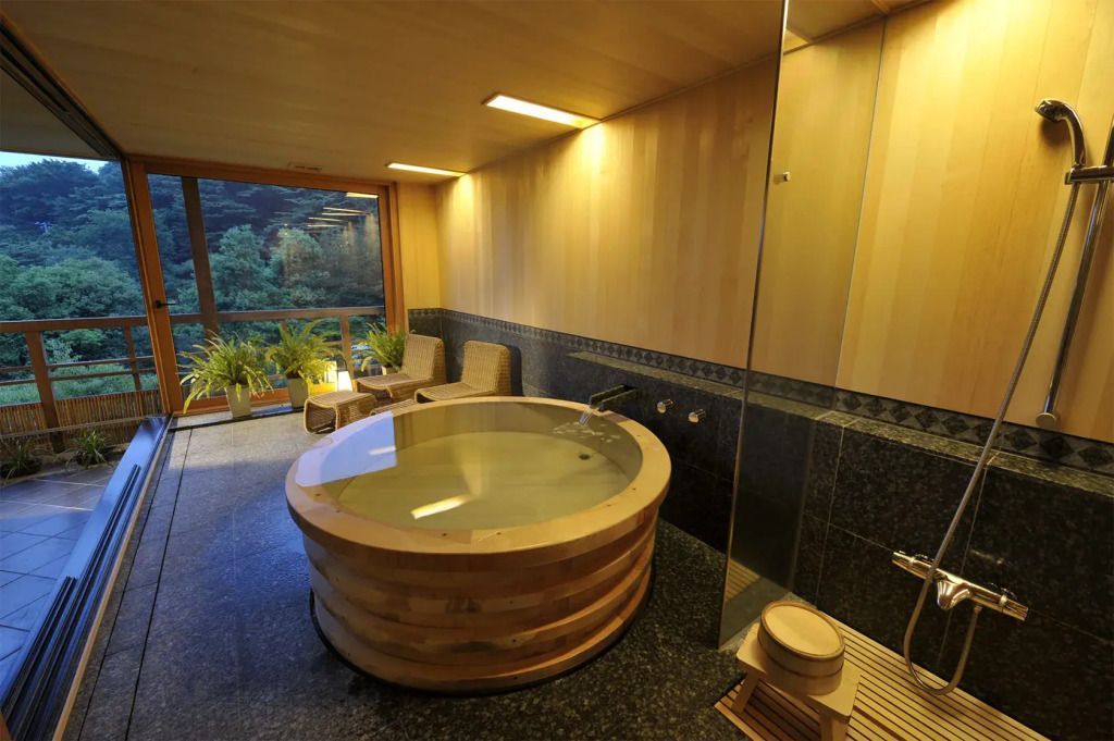 Ein hölzernes Panorama-Bad in einer eleganten Suite mit Aussicht auf Natur.