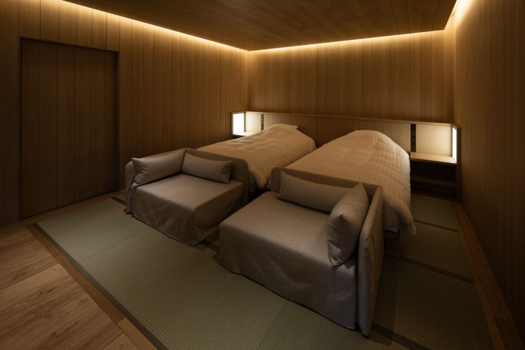 Zwei Betten in einem eleganten, modern beleuchteten Zimmer mit Tatamimatten