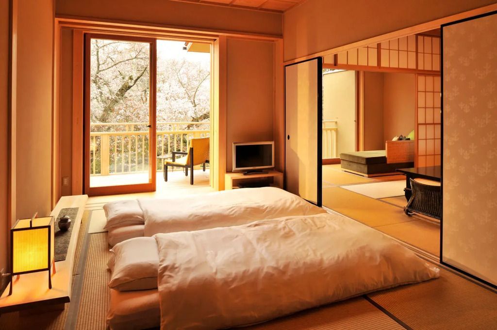 Traditionelles Zimmer mit Futons und Blick auf blühende Kirschbäume.