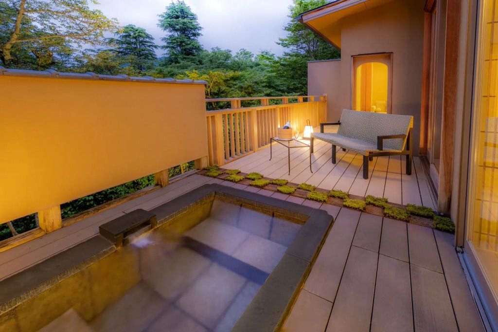 Private Terrasse mit Onsen-Bad und Sitzgelegenheit umgeben von Natur.