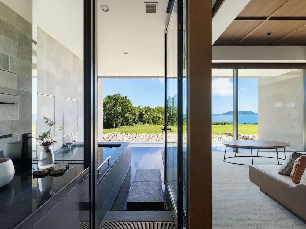 Modernes Hotelzimmer mit großem Fenster und Blick auf Garten und Meer.