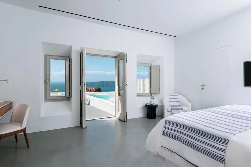 Deluxe Doppelzimmer mit blauweißer Einrichtung und Blick auf das Meer durch offene Türen