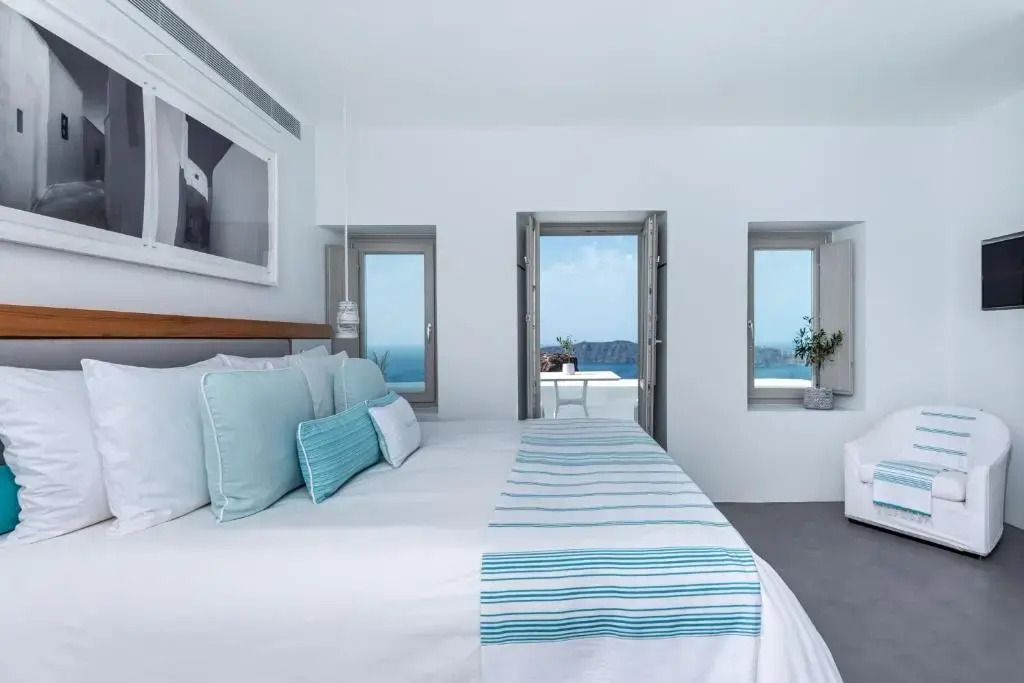 Helles Zimmer mit großem Bett und direktem Zugang zu einem Balkon mit Meerblick