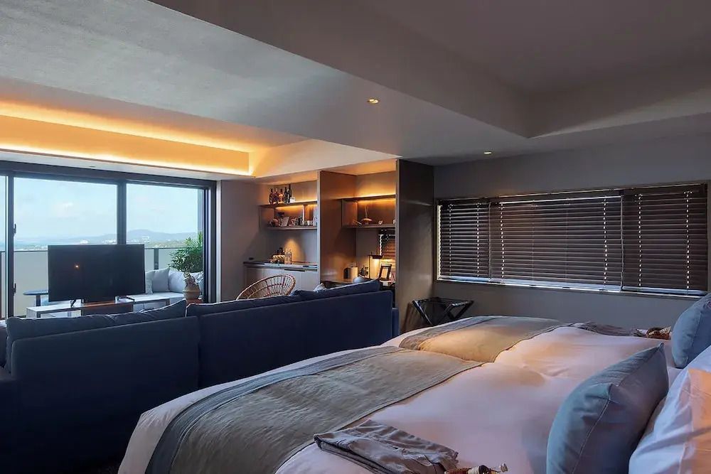 Luxuriöse Suite mit großem Bett, eleganter Beleuchtung und Zugang zu Balkon mit eingeschränkter Sicht.