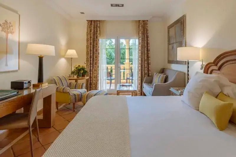 Helles Hotelzimmer mit Doppelbett und Balkon mit Blick ins Grüne, Bahía del Duque