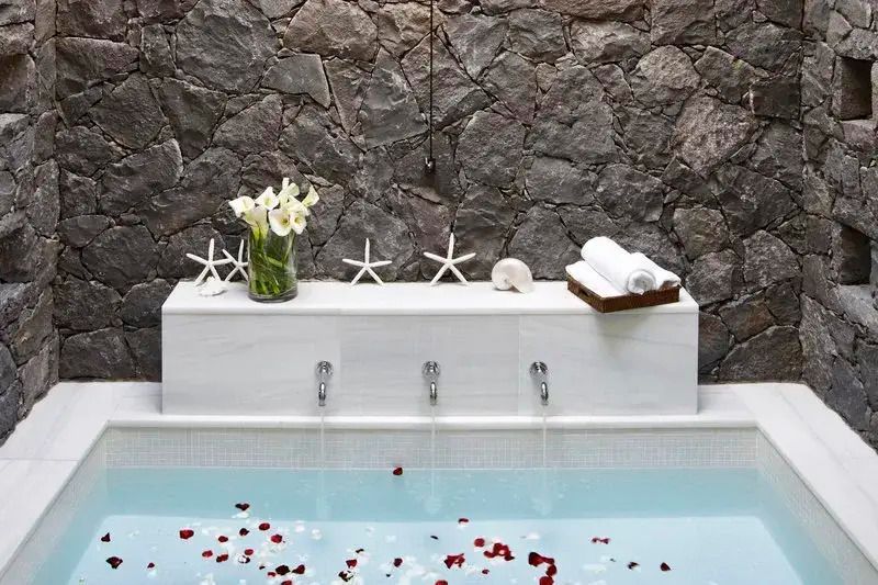 Luxuriöse Badewanne mit Rosenblüten und dekorativen Akzenten