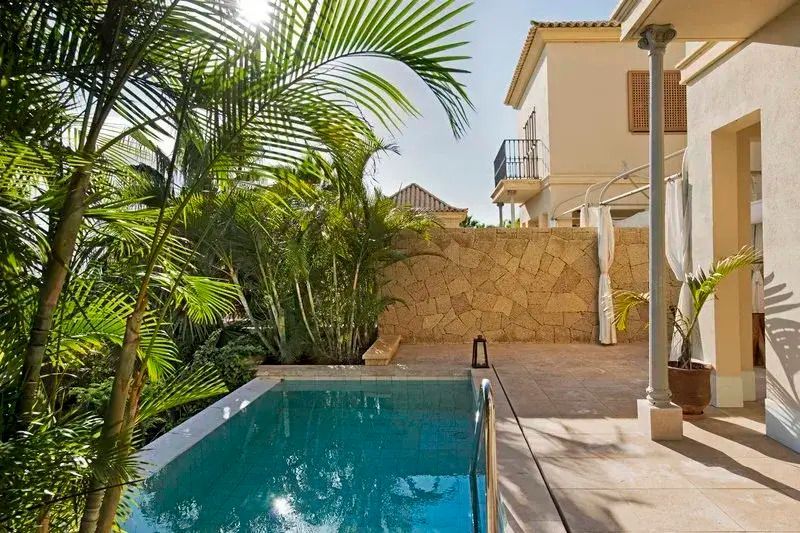 Privater Pool mit tropischen Pflanzen und Blick auf Villenarchitektur