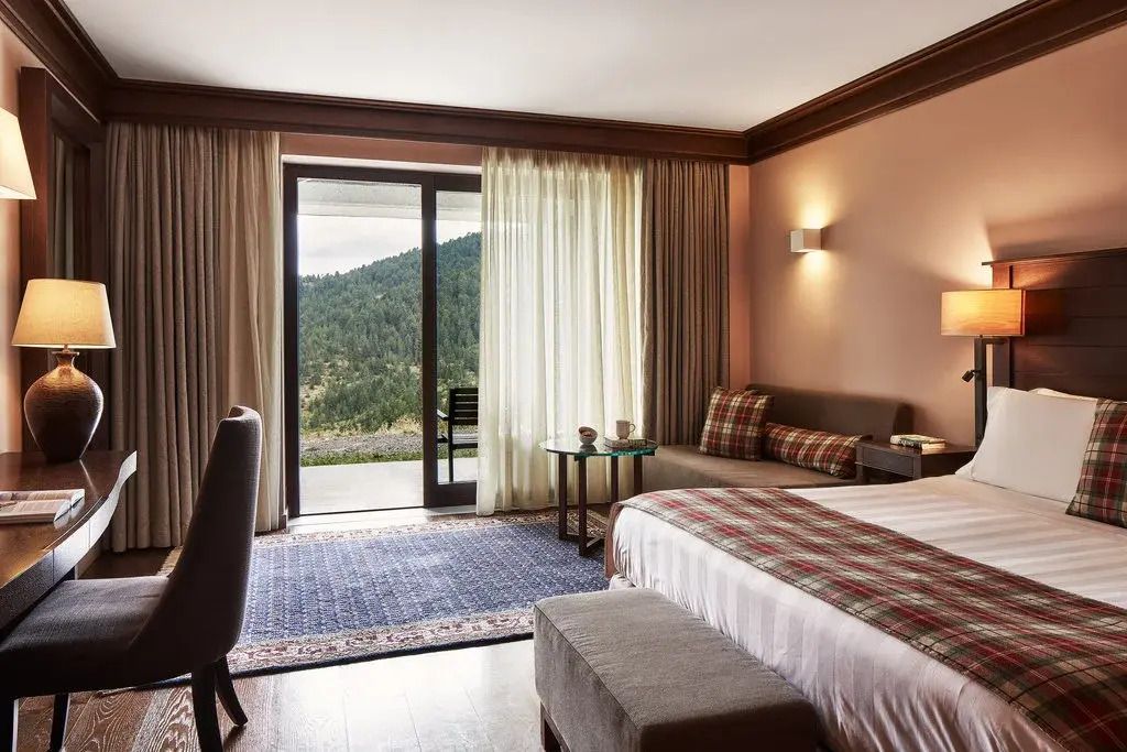 Geräumige Suite mit Doppelbett und Bergblick durch große Fensterfront