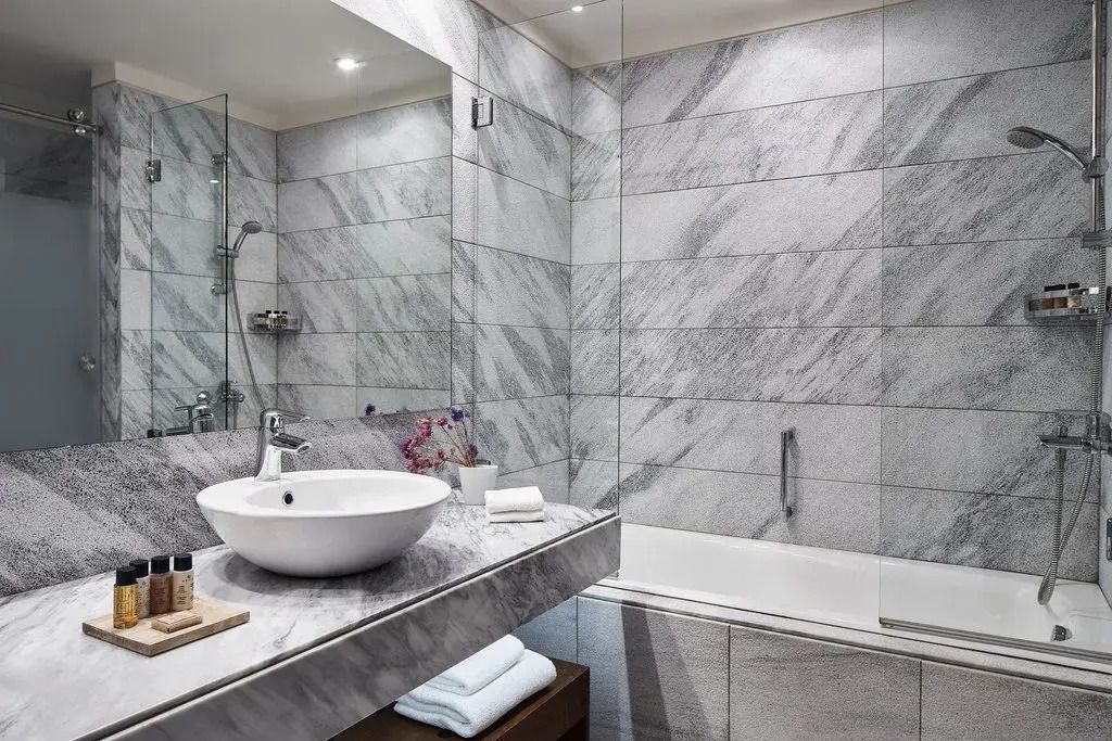Modernes Badezimmer mit grauen Marmorfliesen und stilvollem Waschbecken