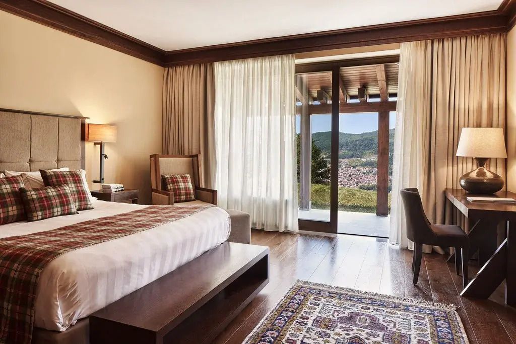 Luxuriöses Schlafzimmer mit Fensterfront und Blick auf die Landschaft