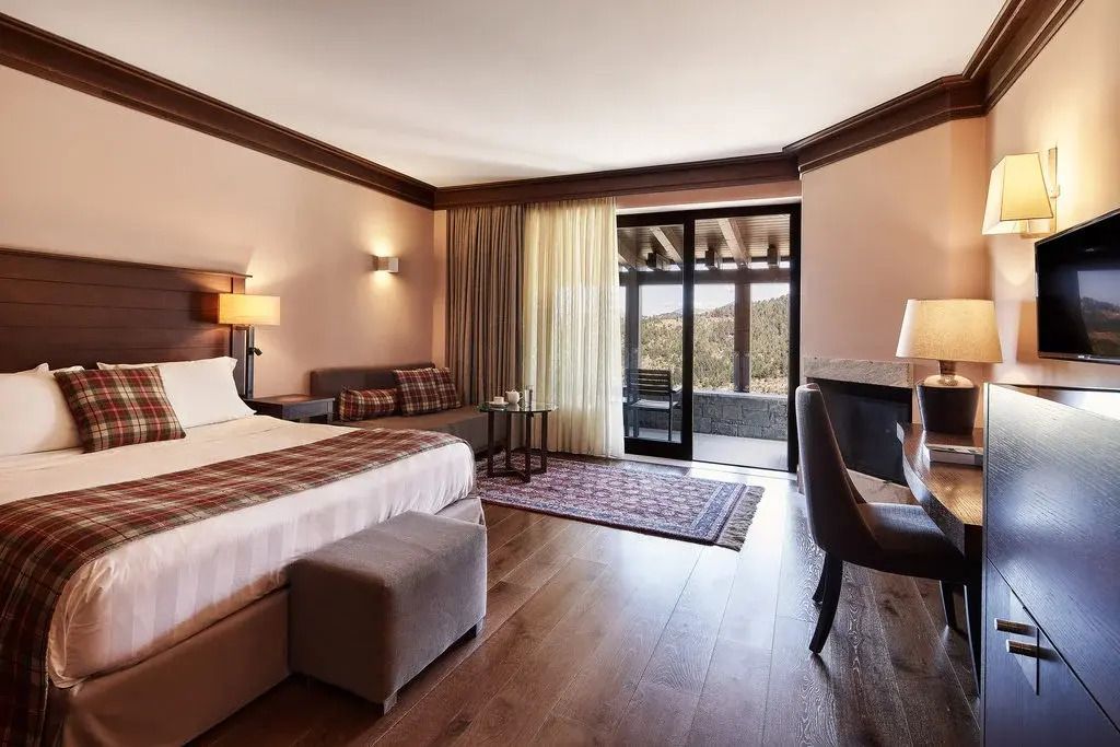 Großzügige Suite mit Doppelbett, Sesseln und Bergblick, warme Holztöne