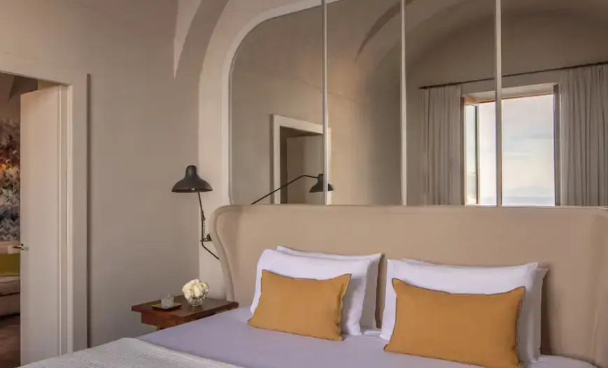 Elegantes Doppelbett in Suite mit stilvollen Kissen und Stehlampe.