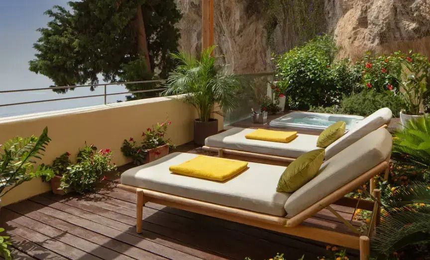 Private Terrasse mit Jacuzzi und Liegestühlen mit Meerblick.