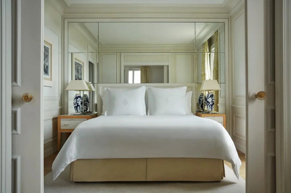 Luxuriöses Doppelbett in neutralen Tönen mit dekorativen Lampen und Spiegelelementen.