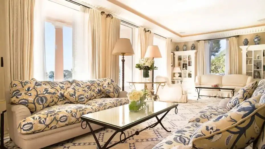 Luxuriöses Wohnzimmer mit stilvollen Sofas, Glastisch und großen Fenstern.