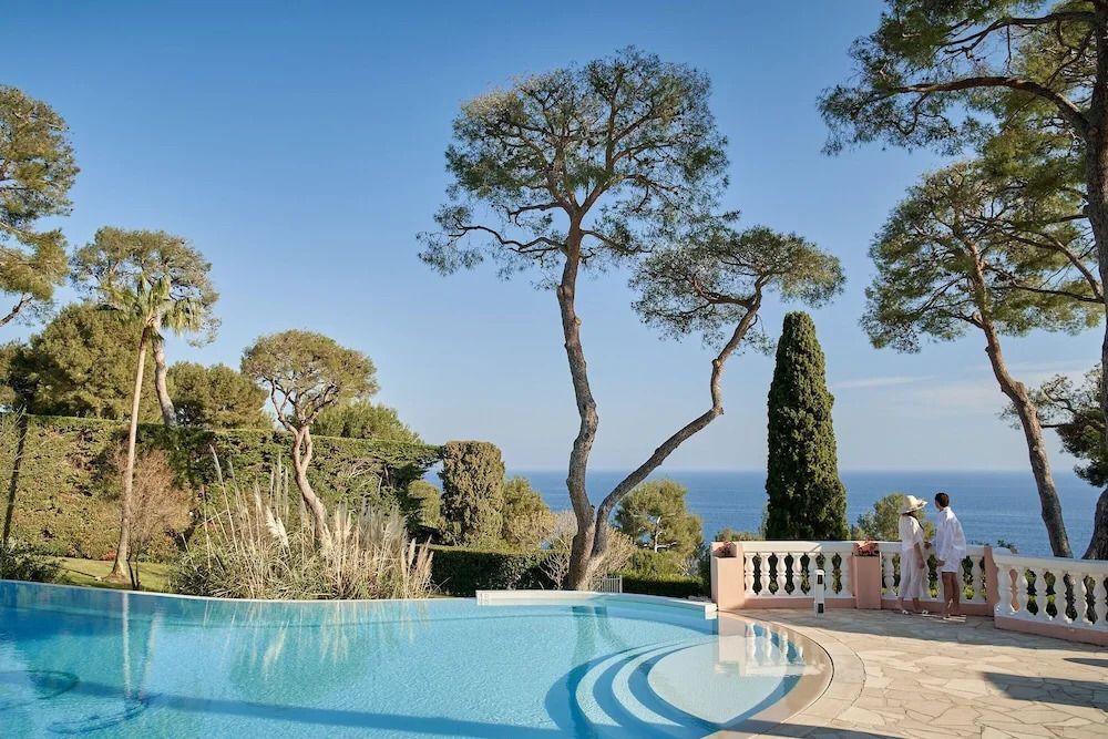 Infinity-Pool mit Blick auf das Meer und umgeben von grünen Bäumen.